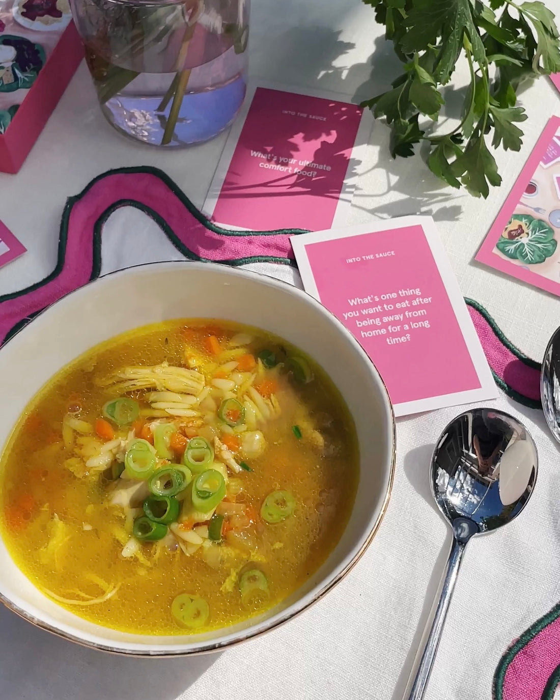 On the left is a bowl of chicken soup, and on the left is the same bowl and the corner of a pink card. @intothesauce, Into the Sauce, Tori Falzon, #intothesauce
